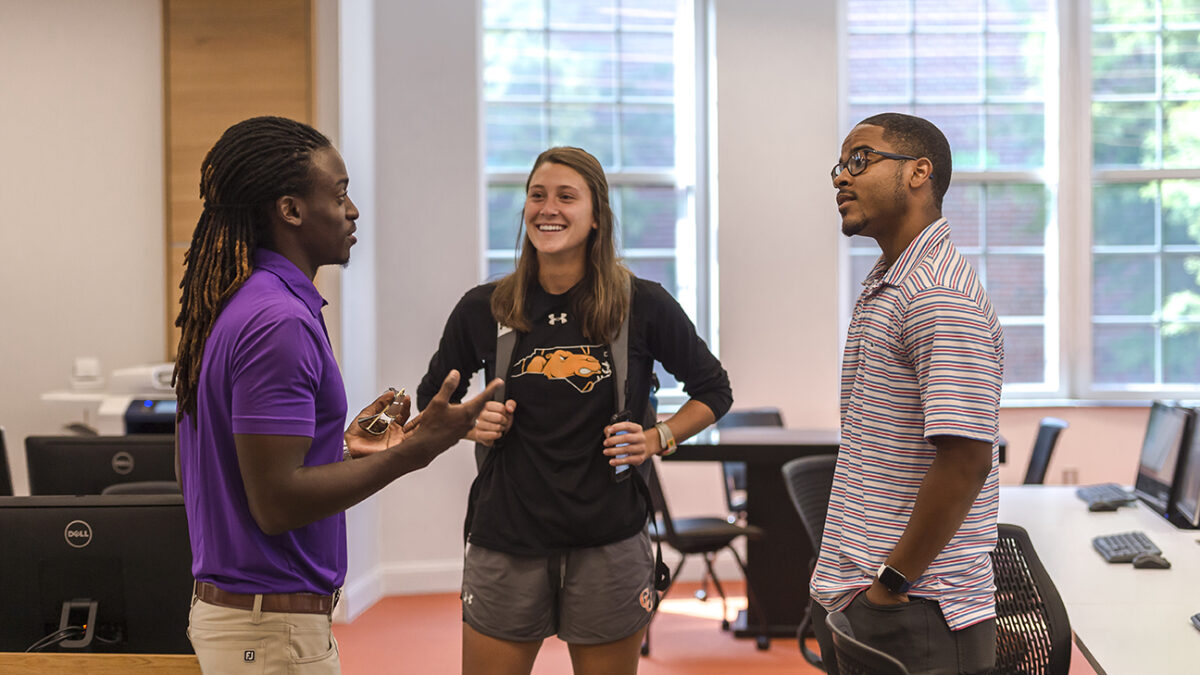 Three students gather after class to chat.